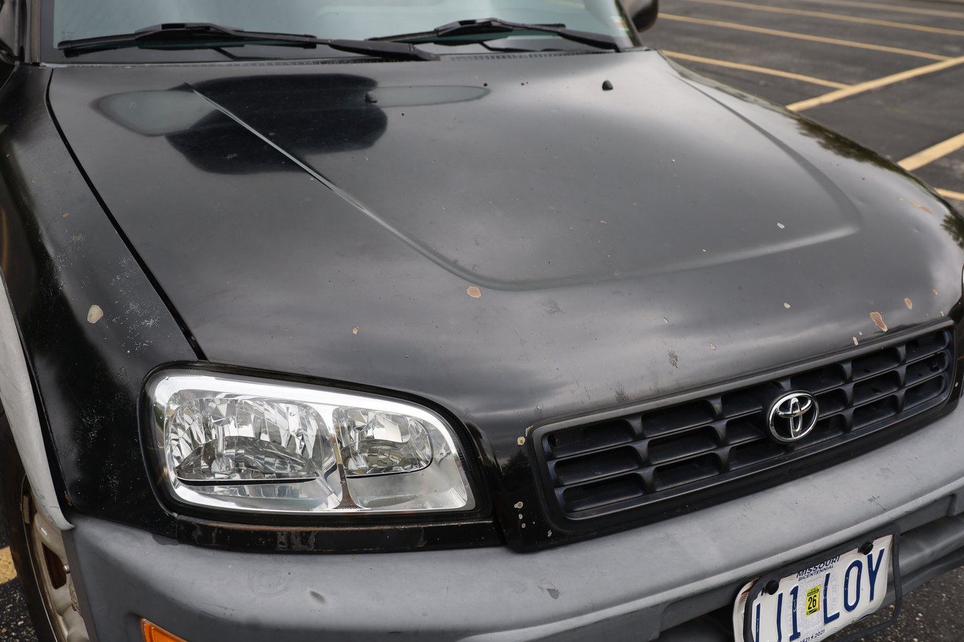 Hood close-up showing chipped paint, slight rust, and small dents